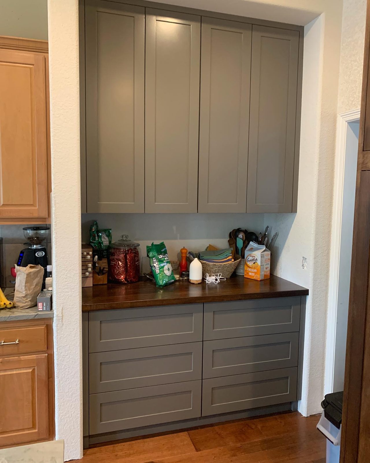 Grey painted butler’s pantry with cabinets to the ceiling and a wood countertop