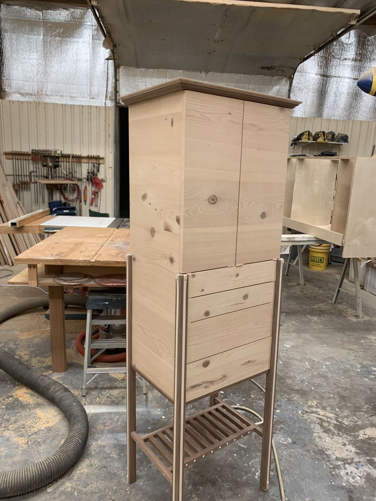 Tall cabinet on a stand with drawers and a slatted lower shelf