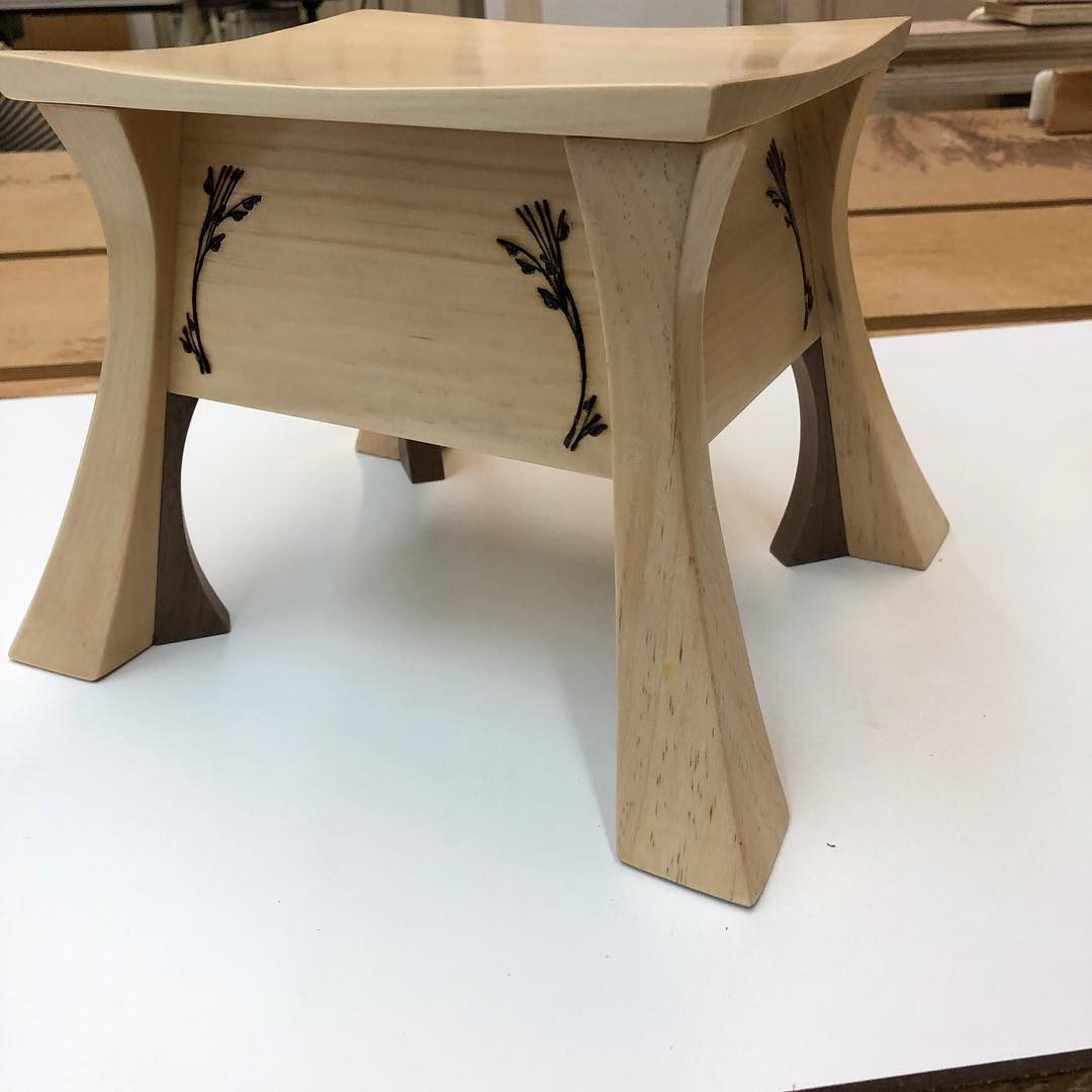 Pale wood side table with flared legs and dark inlaid vine details