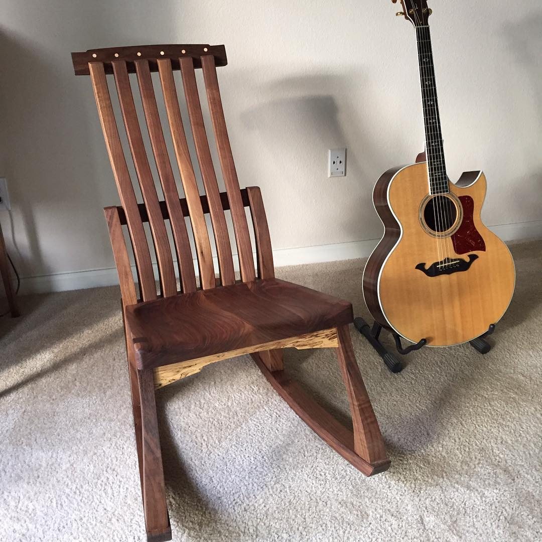 Armless slatted walnut rocking chair beside an acoustic guitar