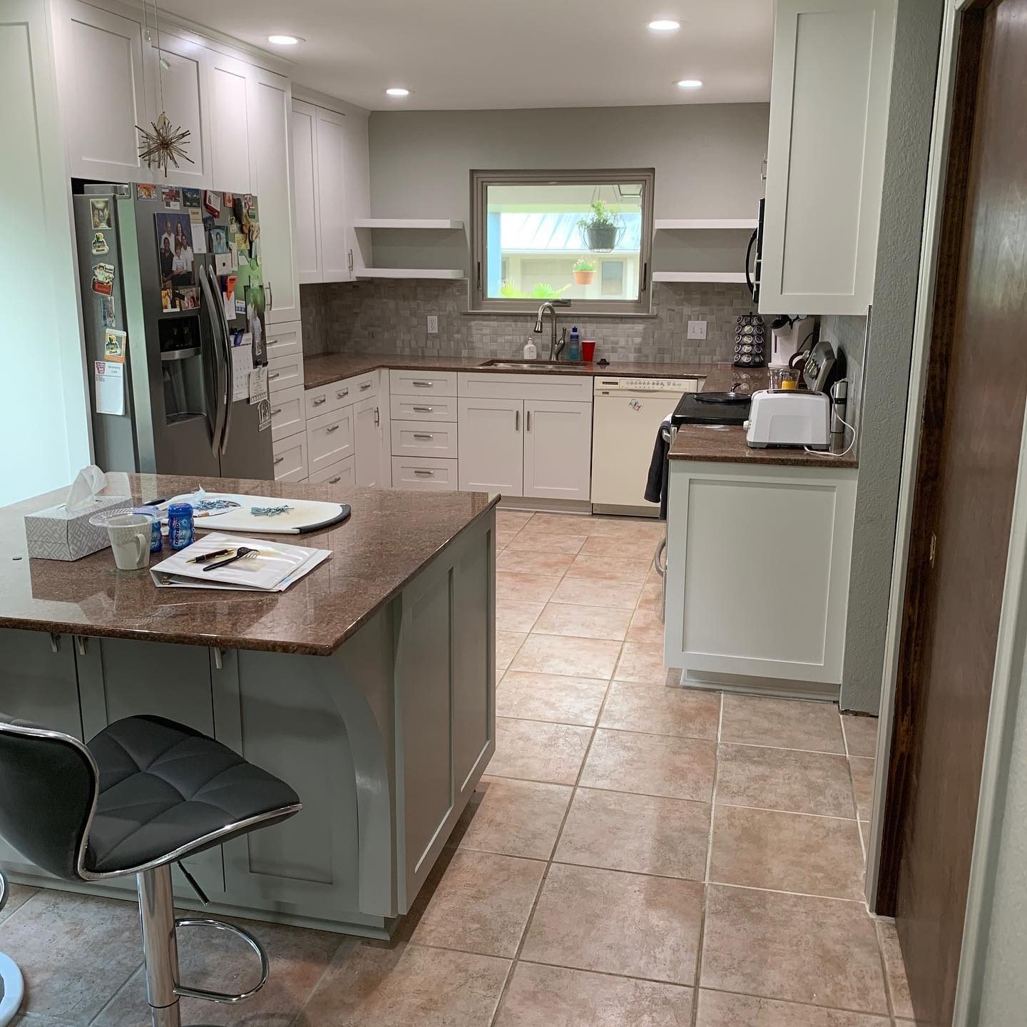 Painted kitchen with a large island, open corner shelves and stainless appliances