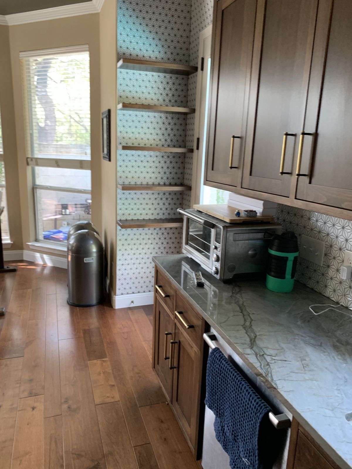 Dark stained kitchen cabinets with stone counters and open floating shelves