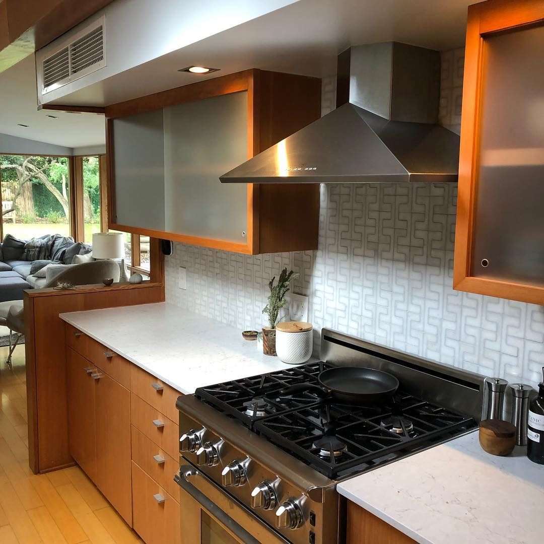 Kitchen with warm wood cabinets, frosted glass uppers and a stainless range hood