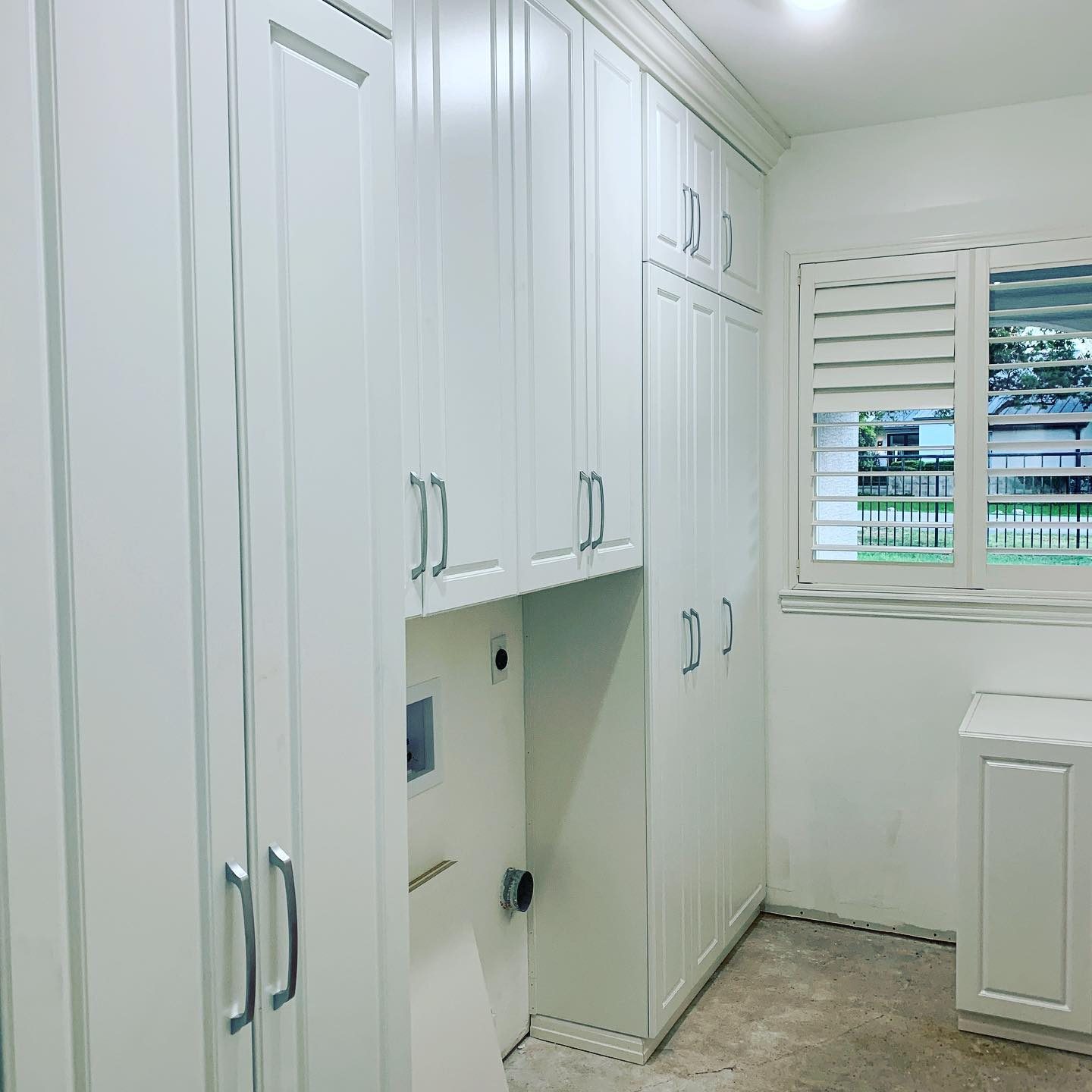 White laundry room with tall painted storage cabinets