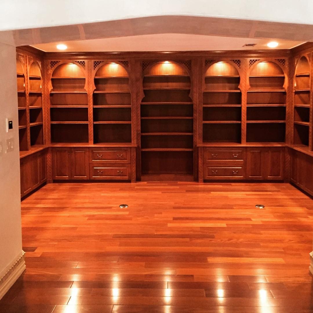 Wall-to-wall library built-ins in a warm stain with arched bays and lit shelves