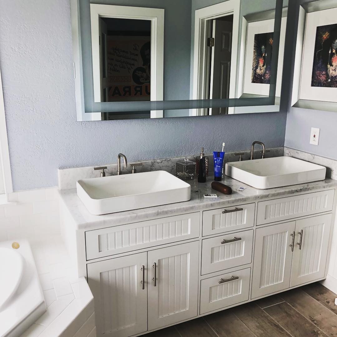 White double vanity with beadboard doors and two vessel sinks
