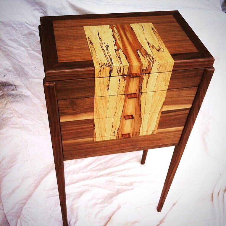 Walnut cabinet on tapered legs with a bold spalted maple stripe down the front